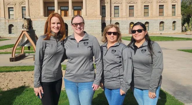 Home Assist Health employees wearing matching grey Home Assist Health quarter-zip long sleeve shirts outside