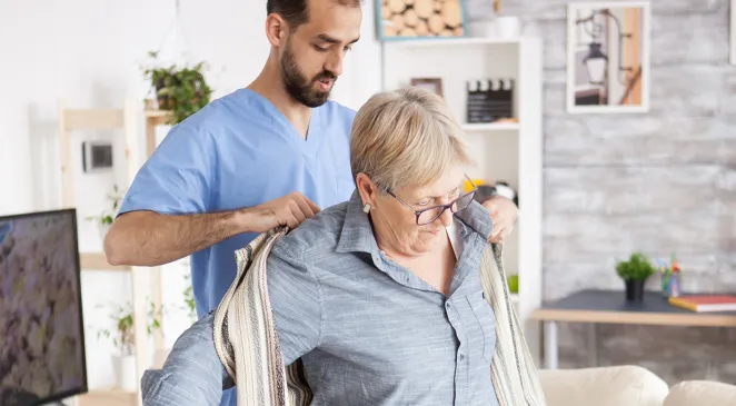 Caregiver helping a senior woman get dressed